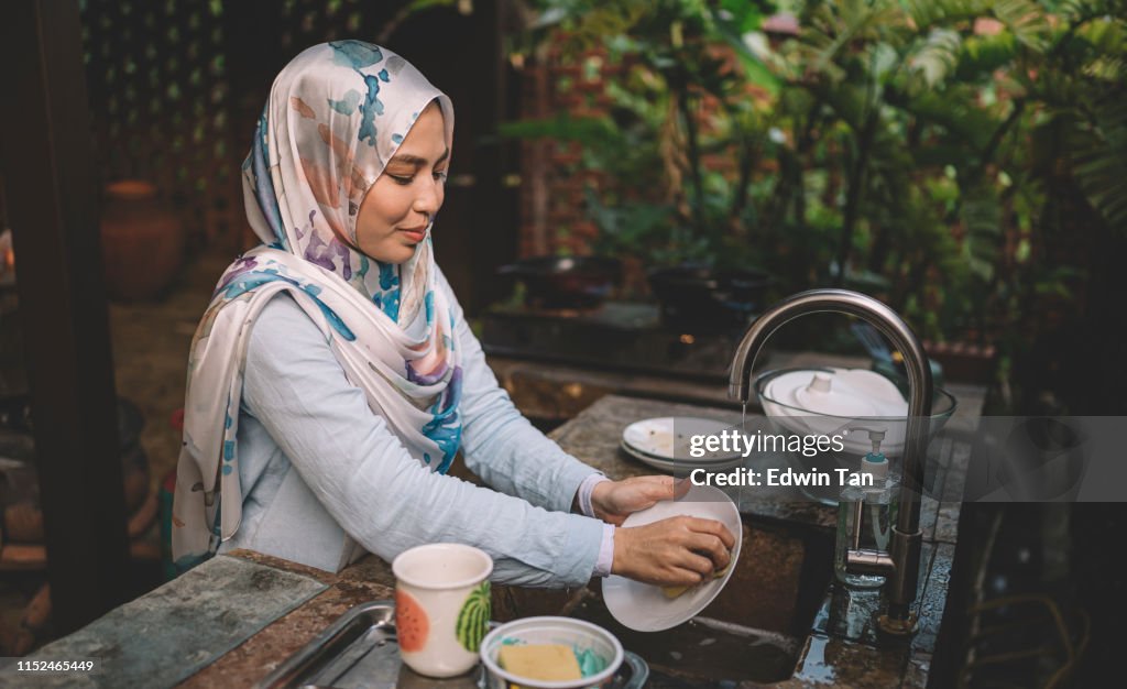 A Malay lady cleaning and washing dishes after dinner party