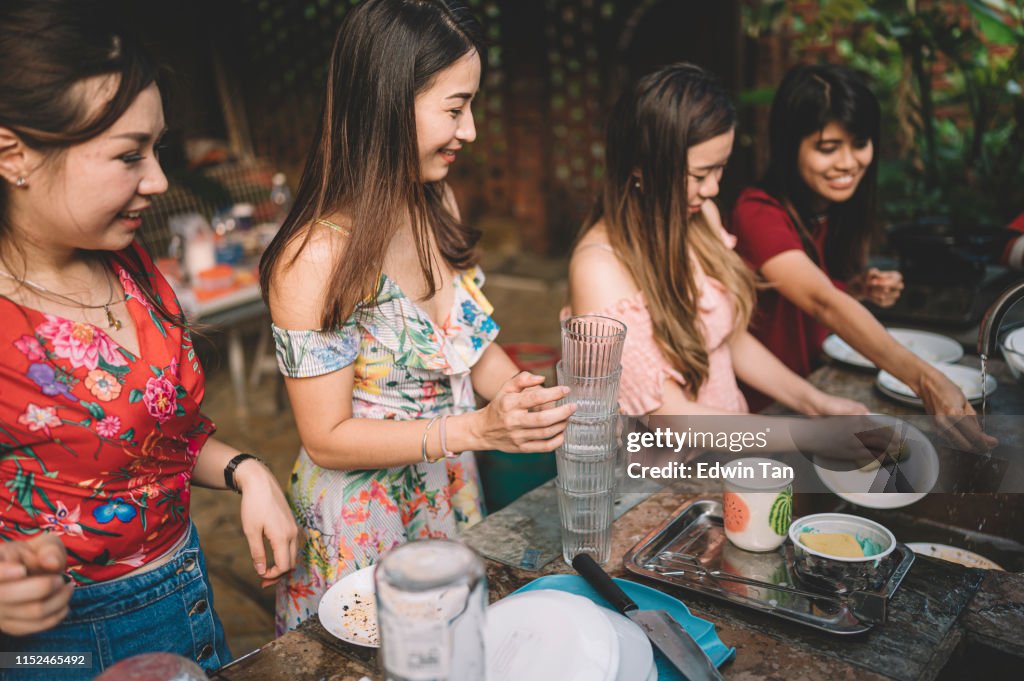 Eine Gruppe asiatischer chinesischer Damen, die nach der Dinner-Party in der Küche Gerichte reinigen