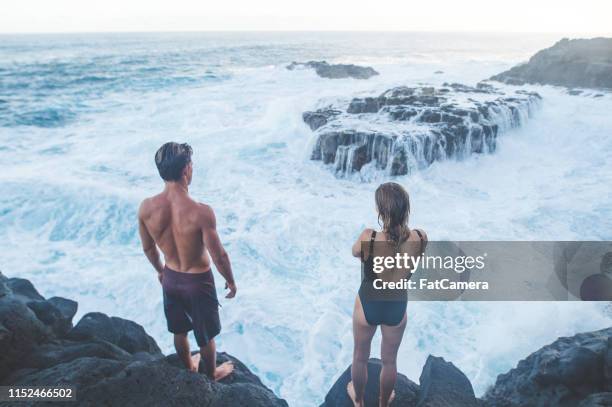 a millennial-age couple getting ready to jump into the ocean - cliff diving stock pictures, royalty-free photos & images