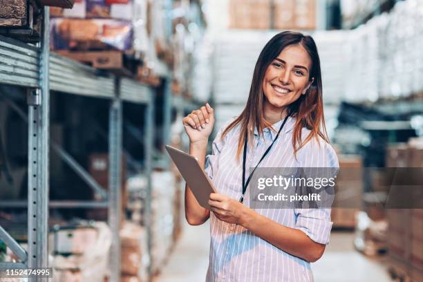 smiling woman holding een digitale tablet in een magazijn - friendly match stockfoto's en -beelden