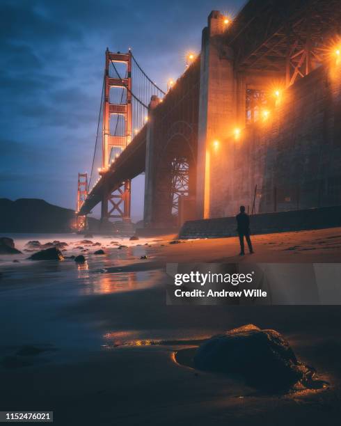 silhouette of a man standing on the beach by the golden gate bridge at night - golden gate bridge night stock-fotos und bilder