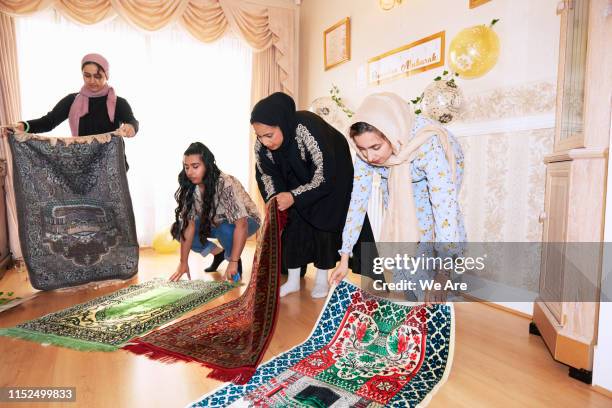 young muslim women arranging prayer mats at home - ramadhan stock pictures, royalty-free photos & images