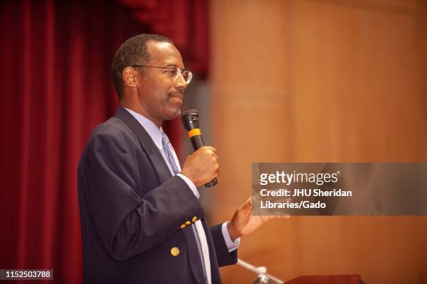 Profile view of neurosurgeon Ben Carson holding a microphone while speaking during a Milton S Eisenhower Symposium at the Johns Hopkins University,...