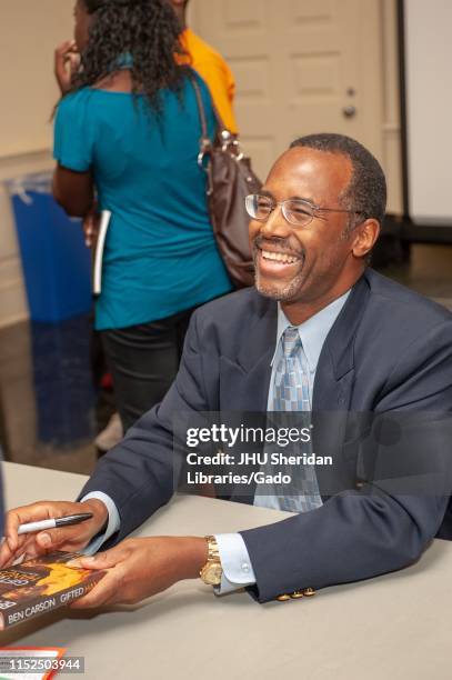 Close-up of neurosurgeon Ben Carson, smiling as he holds his book, during a Milton S Eisenhower Symposium at the Johns Hopkins University, Baltimore,...