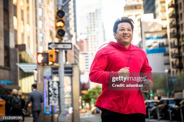 reifer hispanics in stadt - fat guy running stock-fotos und bilder