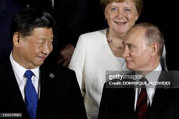 German Chancellor Angela Merkel stands behind Russian President Vladimir Putin and Chinese President Xi Jinping as they arrive to pose for a group...