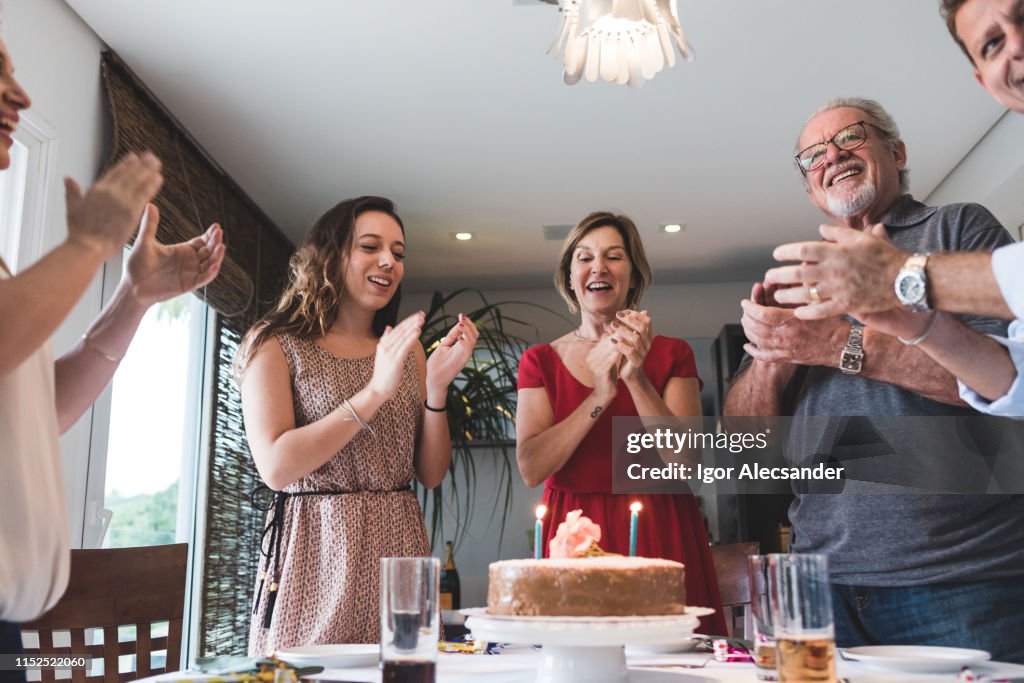 Familia cantando felicitaciones con torta en la mesa y velas