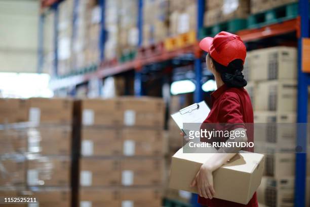 warehouse worker holding cardboard box in logistics warehouse - distribution warehouse stockfoto's en -beelden