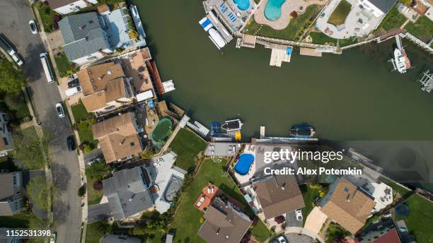 ovanifrån, direkt ovanför drönare bilder av en kanal i oceanside, new york city, med hus med pooler på bakgårdar och bryggor med båtar längs stranden. - nassau county bildbanksfoton och bilder