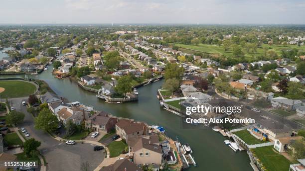 de wealth woonwijk in oceanside, queens, new york city, met huizen met zwembaden op de achtertuin en pieren met boten langs de kanalen. - queens stockfoto's en -beelden