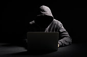 Hacker working on laptop in the dark
