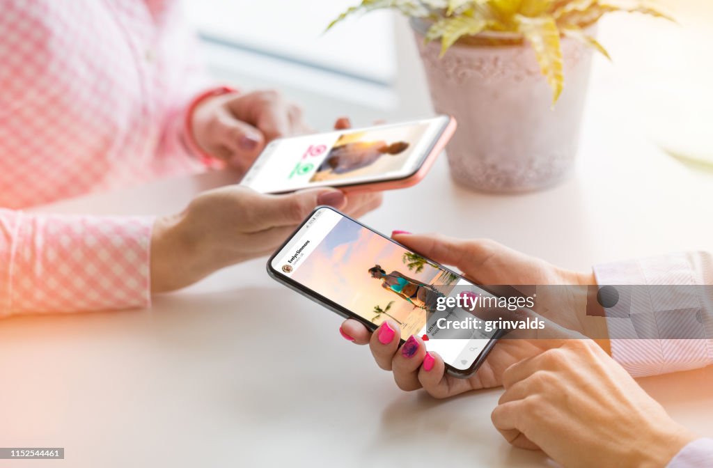 Two women using their mobile phones together