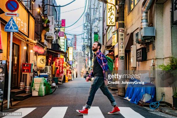 porträt des mannes, der auf der zebra-kreuzung auf der tokioter straße läuft - tokyo japan stock-fotos und bilder