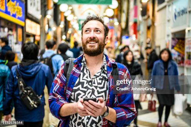 にぎやかな通りを見上げてパターン化されるシャツの観光客の肖像 - tourist ストックフォトと画像