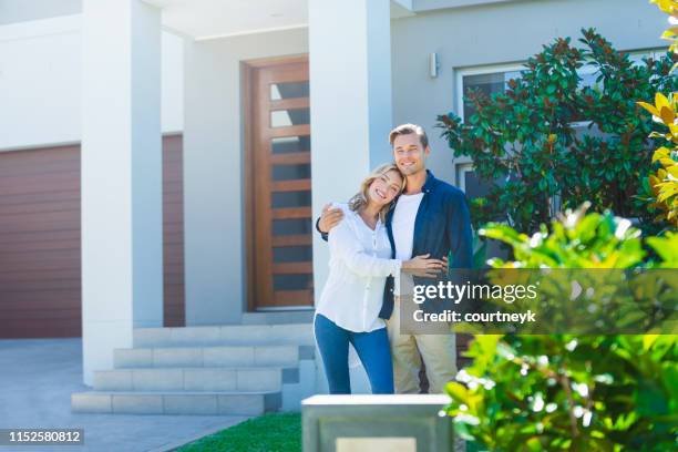 couple standing in front of their new home. - australian garden stock pictures, royalty-free photos & images