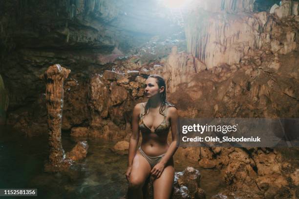 vrouw zittend op rock in cave op flores island - flores stockfoto's en -beelden