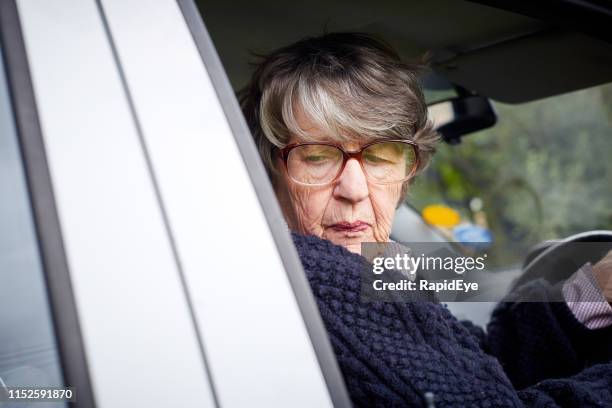 senior woman reversing her car turns her head - woman looking over shoulder serious stock pictures, royalty-free photos & images