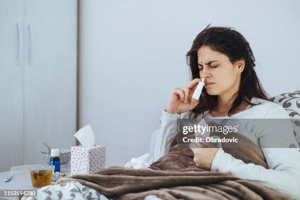 frau erköpft sich an kalten lügen im bett - nasenspray stock-fotos und bilder