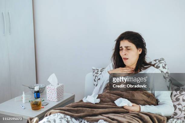 woman suffering from cold lying in bed with tissue - caucasian woman sick in bed coughing stock pictures, royalty-free photos & images
