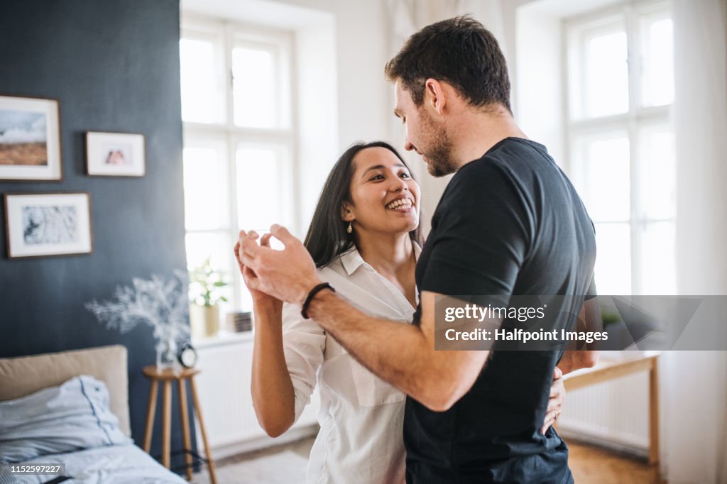 Affectionate young couple in love dancing at home, having fun.