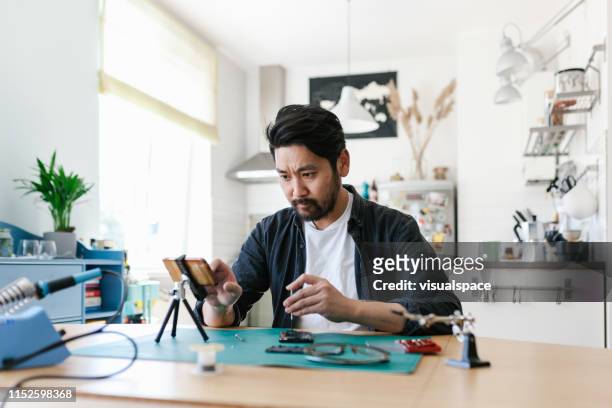 japanese man learns how to repair his smart hone - watching youtube stock pictures, royalty-free photos & images