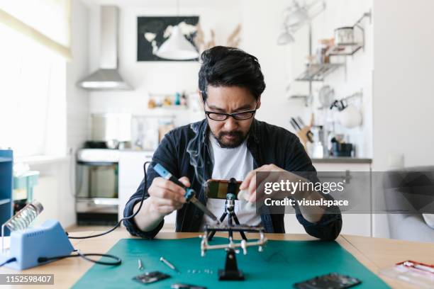 japanese man watching do-it-yourself repairing videos from youtube - soldered stock pictures, royalty-free photos & images