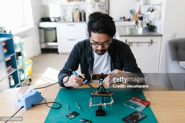 japanese man repairing his smart phone at home - soldered stock pictures, royalty-free photos & images
