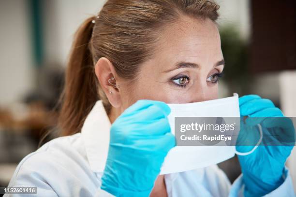 femme scientifique ou professionnel de la santé mettant sur le masque - masque de chirurgien photos et images de collection