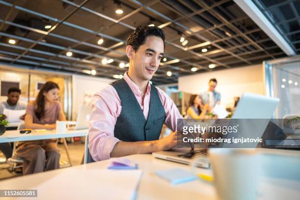 hearing impaired man using lap top at work - hearing loss at work stock pictures, royalty-free photos & images