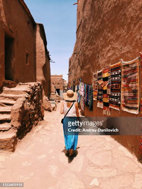 jovencita caminando por estrechas calles de la aldea de ait ben haddou en marruecos - marruecos fotografías e imágenes de stock