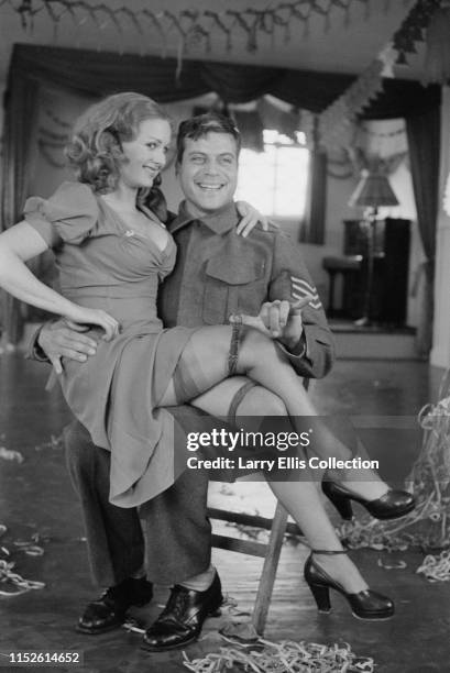 English actor Oliver Reed pictured dressed in character as a British Army Sergeant with actress Jenny Lee-Wright during shooting of the film The...