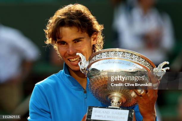 Champion Rafael Nadal of Spain bites the trophy following his record equalling sixth victory during the men's singles final match between Rafael...