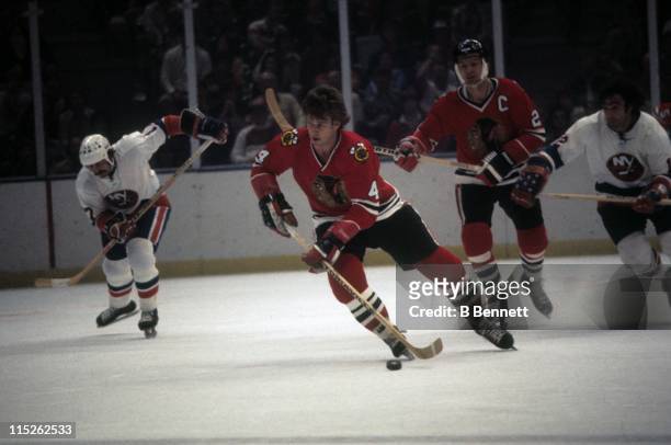 Bobby Orr of the Chicago Blackhawks skates with the puck as Jude Drouin and J.P. Parise of the New York Islanders follow behind along with Stan...
