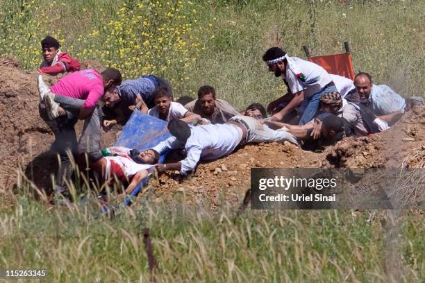 Pro-Palestinian demonstrator is helped after being shot at by Israeli troops, in the Druze village of Majdal Shams, on June 5, 2011 in Israel....