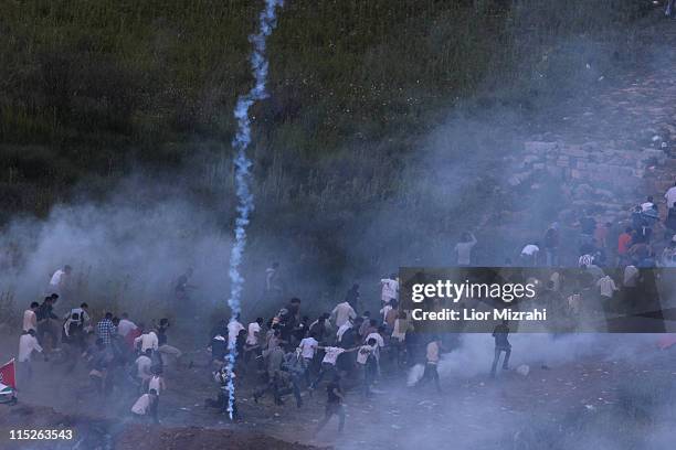 Demonstrators flee Israeli fired tear gas as they gather along Syria's border with Israel while trying to cut through a line of barbed wire and head...
