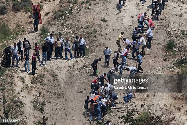 Pro-Palestinian demonstrator is helped after being shot at by Israeli troops, as seen from the Druze village of Majdal Shams, on June 5, 2011 in...