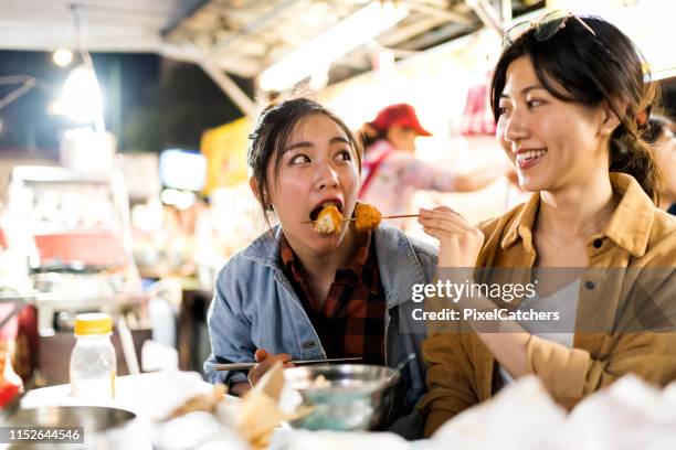 friends trying different street foods at night market - night market stock pictures, royalty-free photos & images