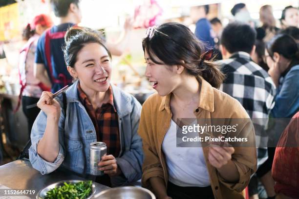 happy friends trying new foods at night market - night market stock pictures, royalty-free photos & images