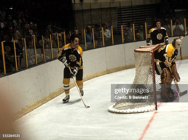 Derek Sanderson of the Boston Bruins skates with the puck around the net as goalie Gerry Cheevers looks on during their NHL game in January, 1972.