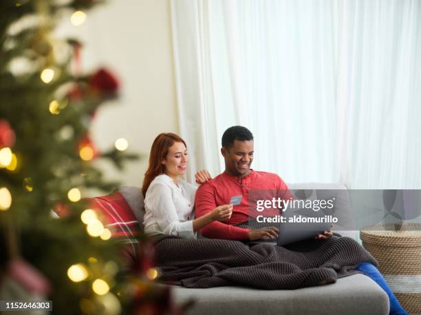 cheerful couple shopping online for christmas - holiday shopping stock pictures, royalty-free photos & images