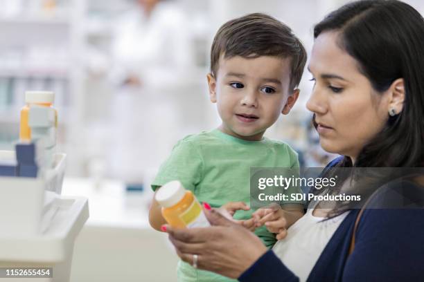 young mother reads labels on medication - prescription label stock pictures, royalty-free photos & images