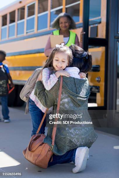 mom hugs young daughter on the first day of school - kids getting off school bus stock pictures, royalty-free photos & images