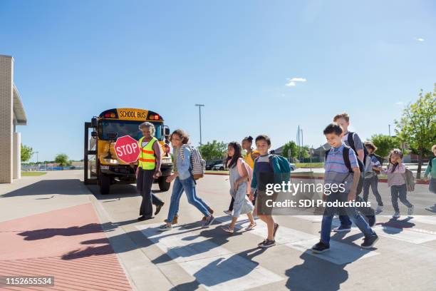 vielfältige gruppe von kindern überquert sicher zur schule - cross road children stock-fotos und bilder