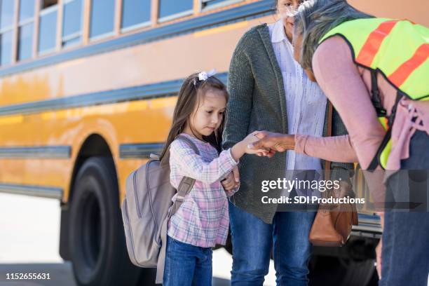 un autista di scuolabus stringe la mano a una timida studentessa - shy foto e immagini stock