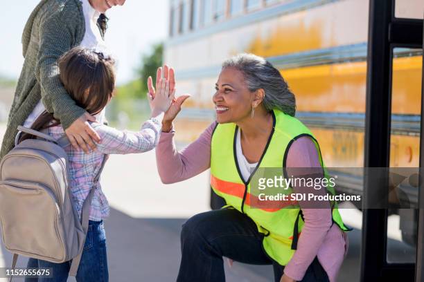 autista di autobus femminile senior high-fives una nuova studentessa - bidello foto e immagini stock