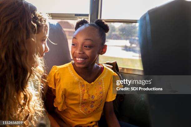 two female friends catch up on school bus - sharing stories stock pictures, royalty-free photos & images