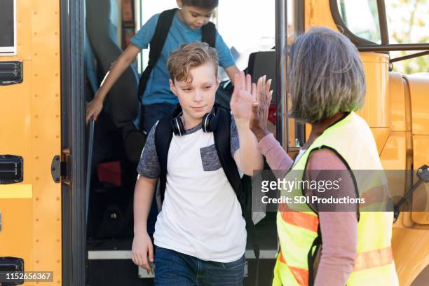 female bus driver high-fives students leaving bus - school caretaker stock pictures, royalty-free photos & images