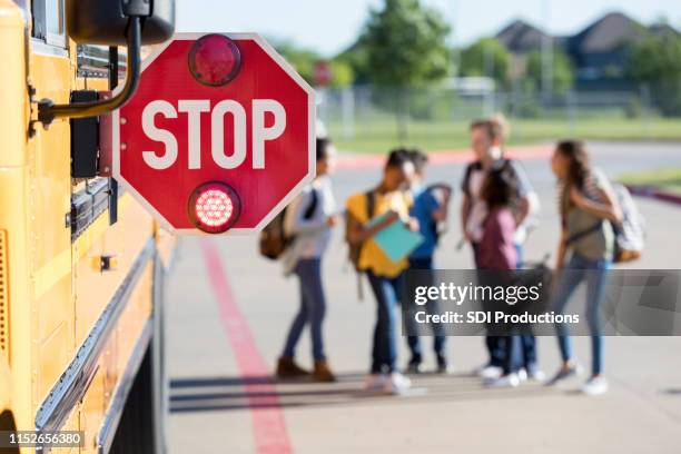 group of school children talk outside bus - bus sign stock pictures, royalty-free photos & images