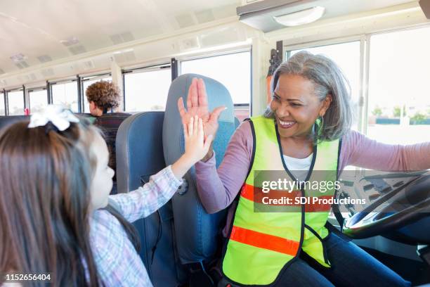 female driver high-fives student boarding school bus - play bus stock pictures, royalty-free photos & images