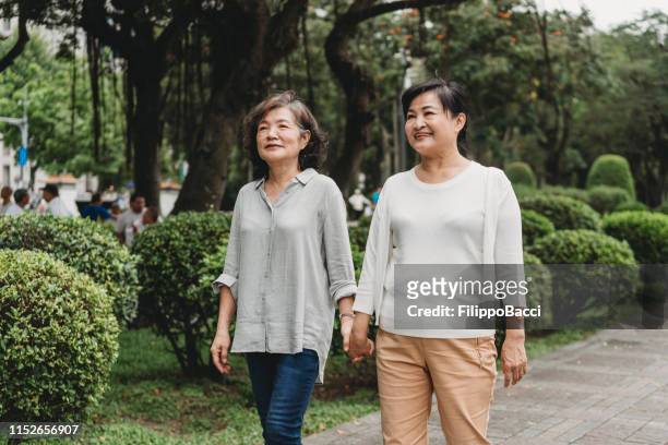 madura pareja de señoras caminando juntos en la ciudad - gay seniors fotografías e imágenes de stock